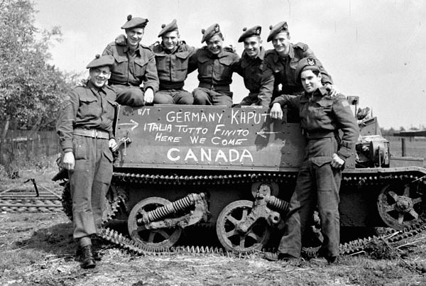 Infantrymen of "D" Company, The Seaforth Highlanders of Canada, with their Universal Carrier, which is inscribed "Germany Kaput - Italia Tutto Finito - Here We Come Canada", De Glindhorst, Netherlands, 5 May 1945. (L-R): Private Wilf Monbourquette, Sergeant Ross MacKay, Privates Hugh McErlain, Lawrence Spence, Harry Campbell, Dusty Millar and Aubrey Bolitho. Date: 5 May 1945 Place: De Glindhorst, Netherlands Extent: 55 x 55 mm Terms of use Credit: Lieut. Michael M. Dean / Canada. Dept. of National Defence / Library and Archives Canada / PA-137741 Restrictions on use: Nil Copyright: Expired Photographer: Michael M. Dean