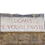 a sign in front of a house in the ruins of Pompeii