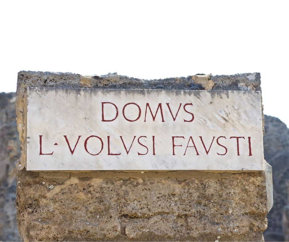 a sign in front of a house in the ruins of Pompeii